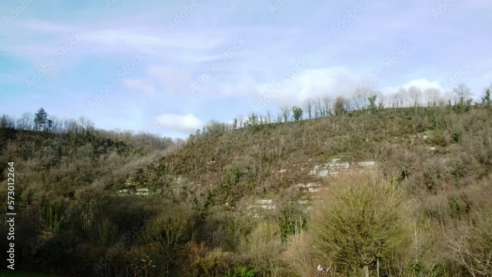 View of a high hill or mountain covered with green vegetation and trees. Sky with small clouds, plain. Countryside in France. View of a high hill or mountain covered with green vegetation and trees. Sky with small clouds, plain. Countryside in France.