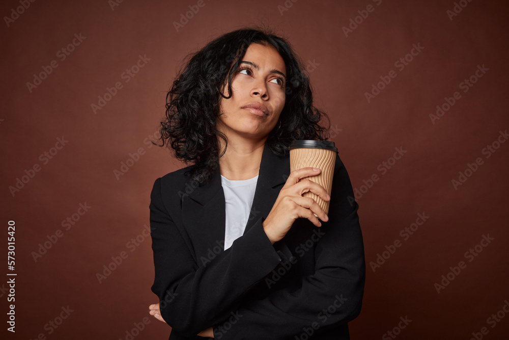 Young business woman drinking a take-away coffee looking sideways with doubtful and skeptical expression. Young business woman drinking a take-away coffee looking sideways with doubtful and skeptical expression.