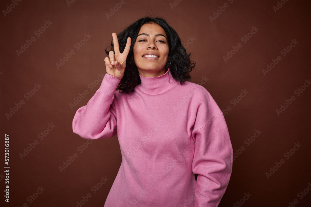Young colombian curly hair woman isolated on brown background showing number two with fingers. Young colombian curly hair woman isolated on brown background showing number two with fingers.