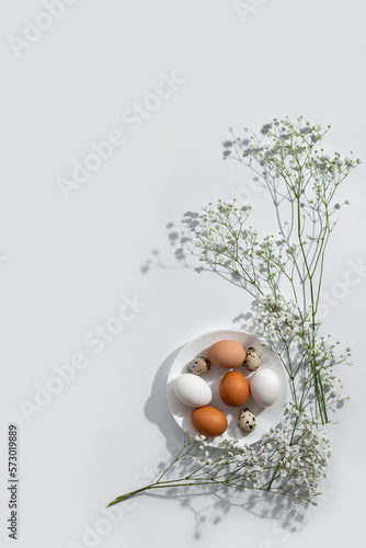 Photography Minimalist aesthetic Easter floral decoration, natural color eggs on plate and flowers on light neutral background