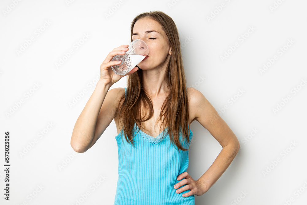 Young woman drinking water from a glass on a white background Young woman drinking water from a glass on a white background