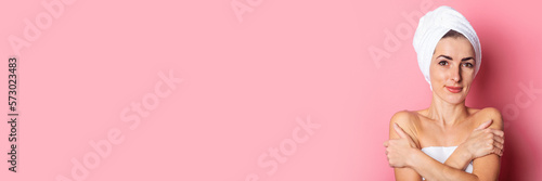spa treatments, smiling young woman with a towel on her head on a pink background. Banner.
