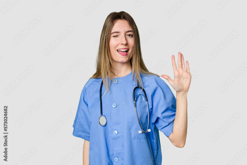 Young female nurse in uniform with stethoscope, symbol of care and dedication to patients laughs out loudly keeping hand on chest. Young female nurse in uniform with stethoscope, symbol of care and dedication to patients laughs out loudly keeping hand on chest.