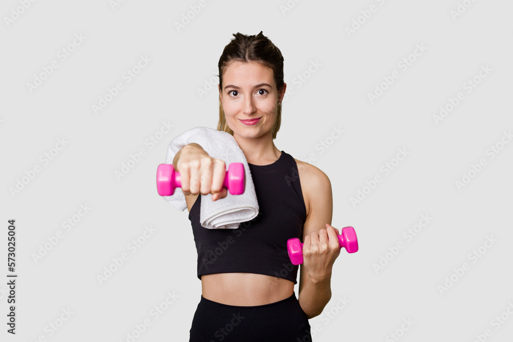 Young female athlete lifting weights, focused and determined in indoor studio Young female athlete lifting weights, focused and determined in indoor studio