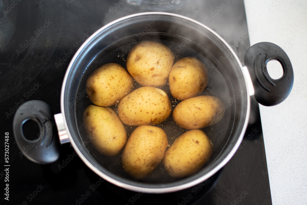 Varias patatas cociéndose en una olla con agua hirviendo. Concepto de preparar una receta con patatas cocidas. Agua en ebullición Varias patatas cociéndose en una olla con agua hirviendo. Concepto de preparar una receta con patatas cocidas. Agua en ebullición