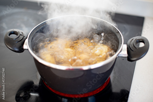 Varias patatas cociéndose en una olla con agua hirviendo. Concepto de preparar una receta con patatas cocidas. Agua en ebullición