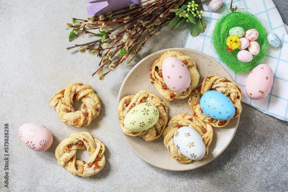 Obraz premium Easter composition. Sweet Italian Easter Bread Rings from puff pastry and dyed eggs on a stone background. View from above.