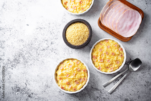 Cheesy millet with ham slices in a baking bowl