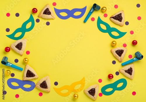 Hamantaschen Cookies, Carnival Mask, Noisemaker on Yellow Background. Purim Celebration, Jewish Carnival Holiday Concept.