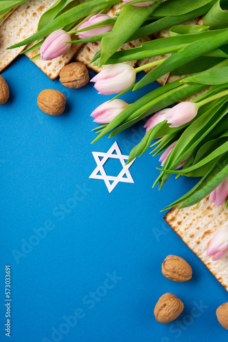 Fototapeta Naklejka Na Ścianę i Meble -  Passover Greeting Card with Mfatzah, Nuts and Pink Tulip Flowers on Blue Background.