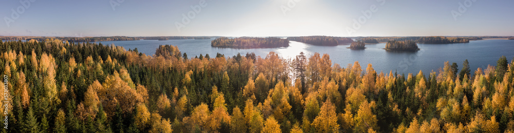 Aerial landscape panorama with mixed forest with autumn colours by Nordic lake.