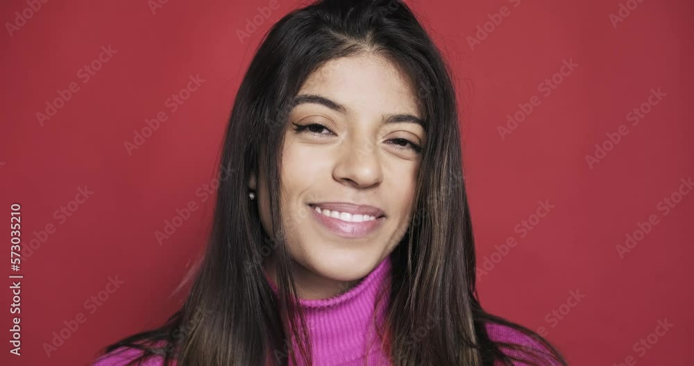 Close up slow motion face of young woman, isolated on red background Close up slow motion face of young woman, isolated on red background