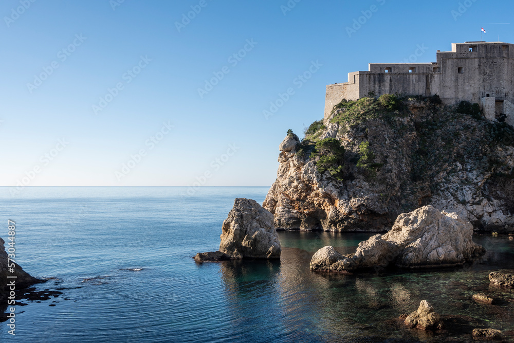 Beautiful Lovrinac fortress, on of many prominent Dubrovnik city medieval walls, rising above steep, sharp cliffs and blue Adriatic sea