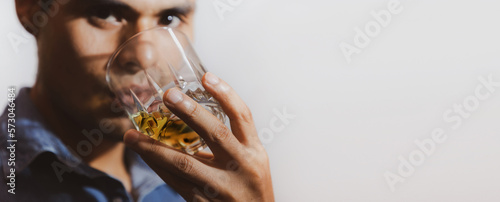 hombre joven triste y mirando con bebida en su mano en un fondo gris y espacio para texto, concepto de problemas con las bebidas alcohólicas, depresión, alcoholismo.  photo