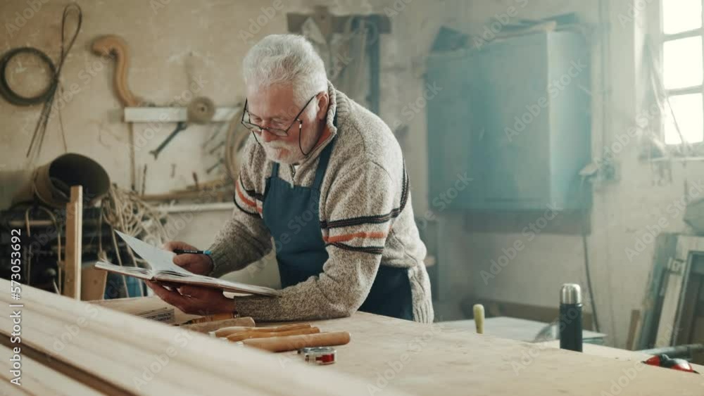 Teenage grandson helps his carpenter grandfather in the workshop. Concept of Handmade, Profession and Hobby. Teenage grandson helps his carpenter grandfather in the workshop. Concept of Handmade, Profession and Hobby.