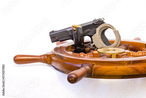 9mm pistol, bullets, clip, handcuffs and a ships wheel with copy space photo