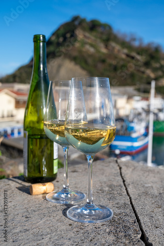 Tasting of txakoli or chacolí slightly sparkling very dry white wine produced in Spanish Basque Country with view on old port and village Getaria, Spain photo