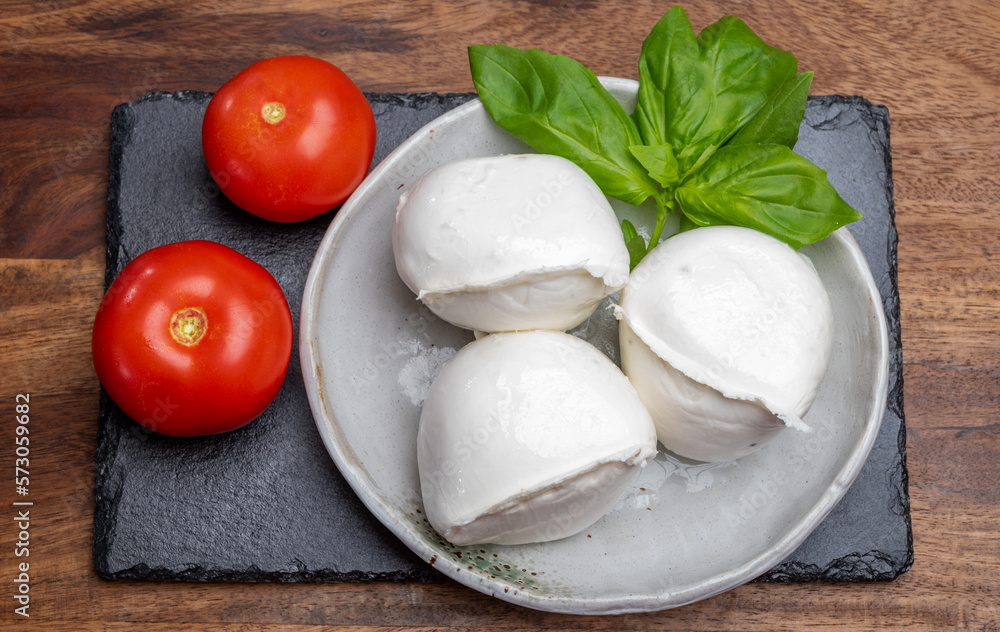 White balls of Italian soft cheese Mozzarella di Bufala Campana served with fresh green basil and red tomato White balls of Italian soft cheese Mozzarella di Bufala Campana served with fresh green basil and red tomato