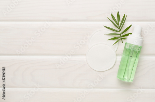 Foaming facial cleanser and with eco pads on wooden background  top view