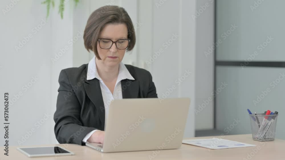 Old Businesswoman Typing on Laptop in Office Old Businesswoman Typing on Laptop in Office