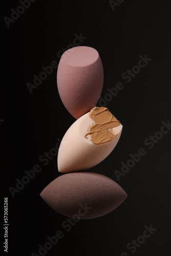 Cuadro en lienzo Three different beauty blenders on a black background with foundation
