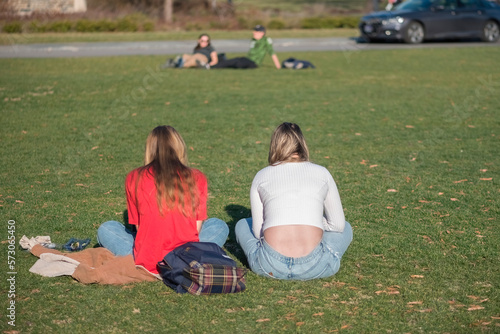 Couple of young student women sitting on grass