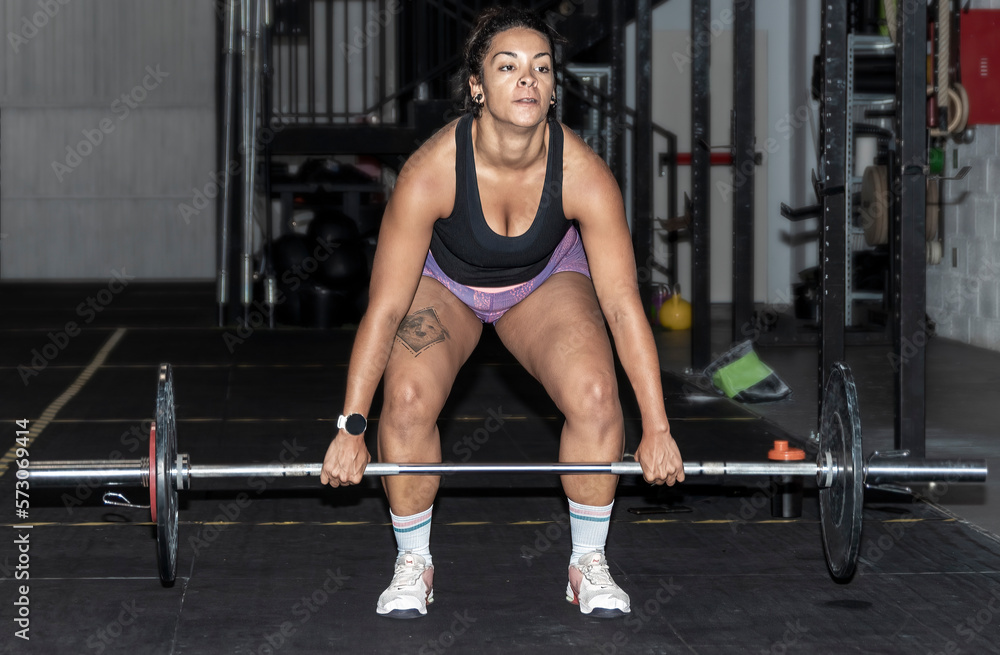 Fototapeta premium Latin woman lifting weight in the gym