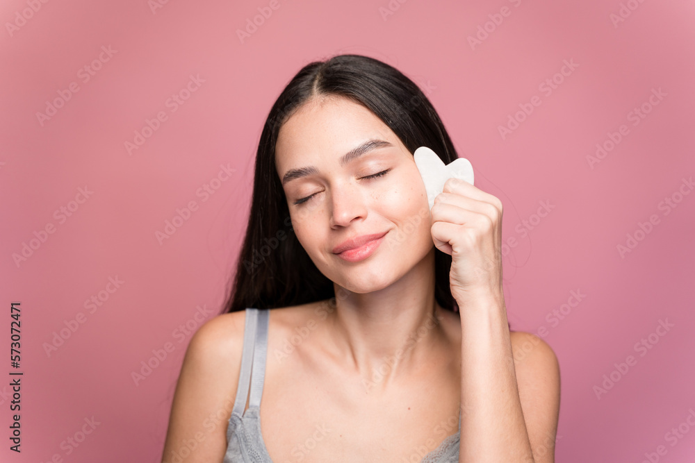 Smiling woman with massaging her face with a wasa stone Smiling woman with massaging her face with a wasa stone