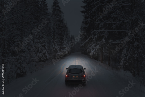 Driving a car on a forest snowy road at night. Headlights light the way