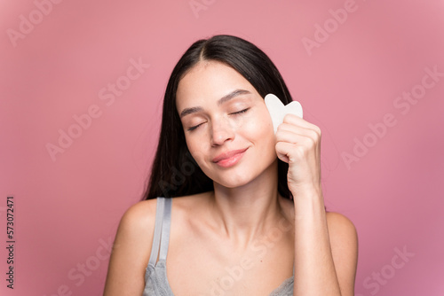 Smiling woman with massaging her face with a wasa stone