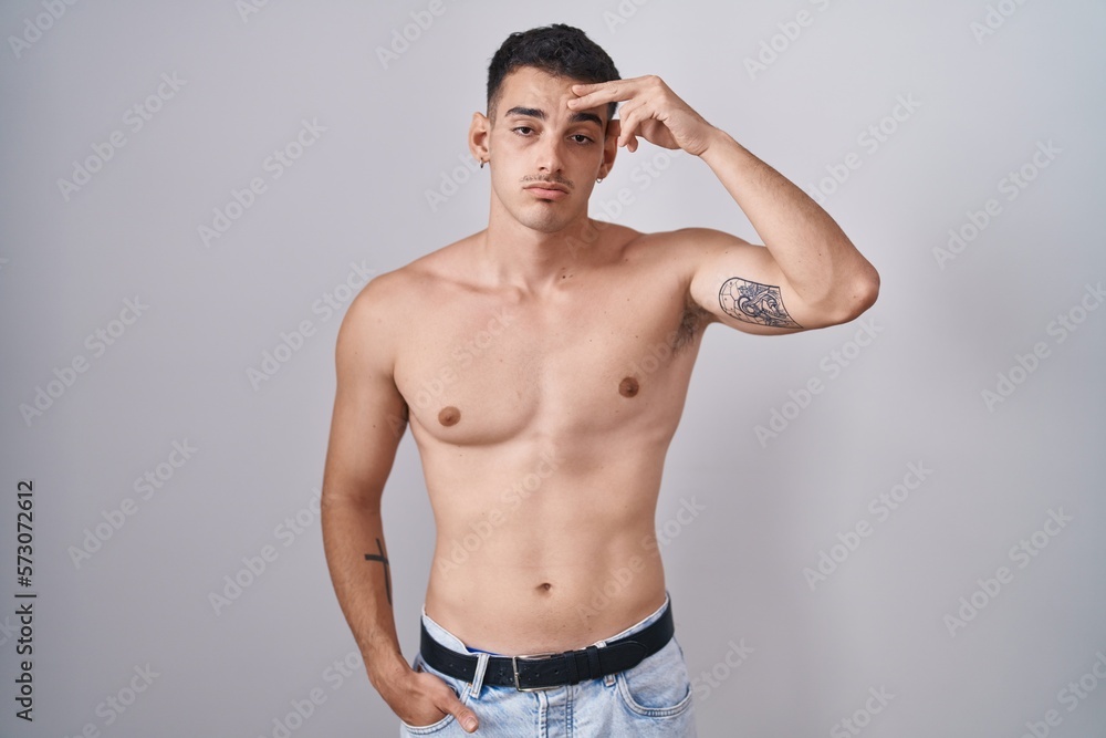 Fototapeta premium Handsome hispanic man standing shirtless worried and stressed about a problem with hand on forehead, nervous and anxious for crisis