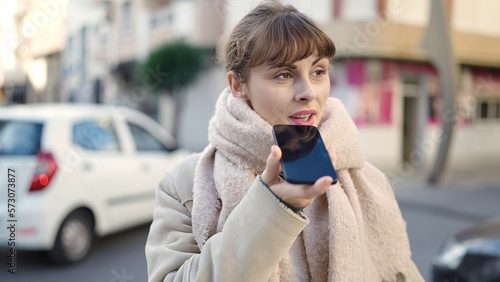 Young caucasian woman recording voice message at street