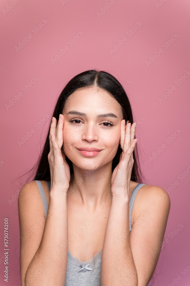 Smiling woman with closed eyes applying moisturizing cream to her face Smiling woman with closed eyes applying moisturizing cream to her face