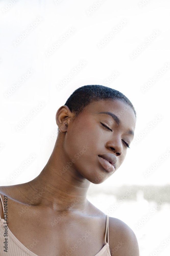Fototapeta premium Black woman standing with closed eyes against sunlight
