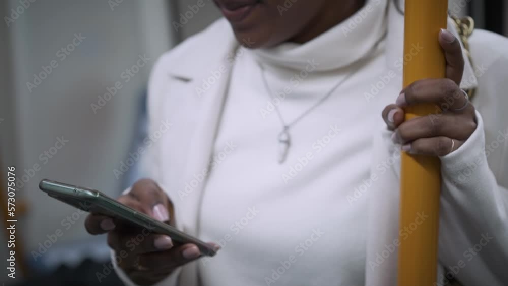Pretty young African girl standing using cell phone in subway. Beautiful happy black woman consulting phone on transport. Cosmopolitan people moving around the city. Pretty young African girl standing using cell phone in subway. Beautiful happy black woman consulting phone on transport. Cosmopolitan people moving around the city.