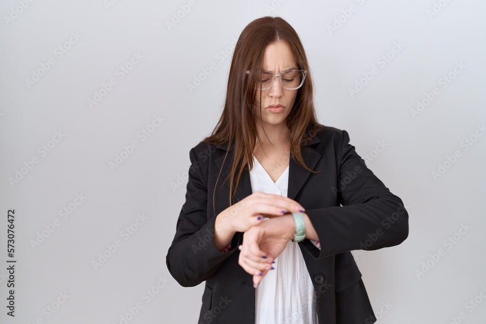 Beautiful brunette woman wearing business jacket and glasses checking the time on wrist watch, relaxed and confident Beautiful brunette woman wearing business jacket and glasses checking the time on wrist watch, relaxed and confident