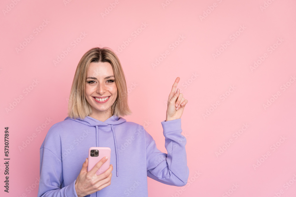 Cheerful woman with smartphone pointing aside Cheerful woman with smartphone pointing aside