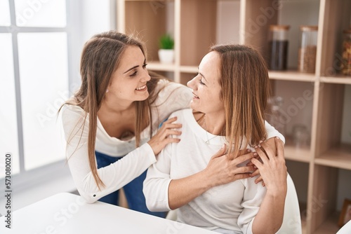 Two women mother and daughter hugging each other at home