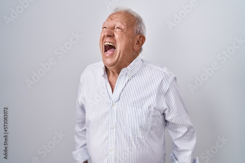Senior man with grey hair standing over isolated background angry and mad screaming frustrated and furious, shouting with anger. rage and aggressive concept. © Krakenimages.com