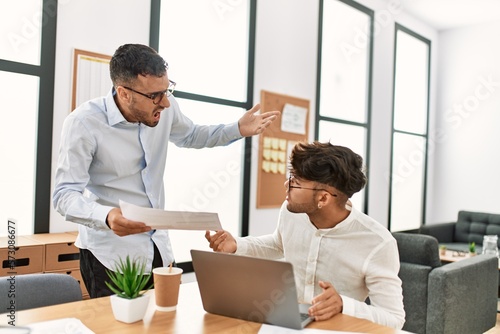 Two hispanic men business workers arguing at office