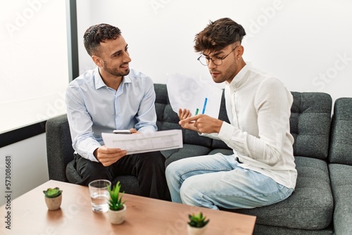 Two hispanic men business workers reading document working at office