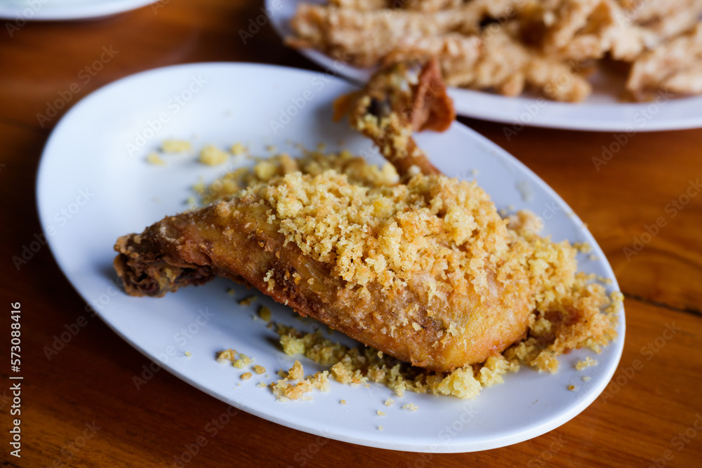 Ayam Goreng Kremes. Popular fried chicken dish from Jogjakarta, deep-fried whole chicken and topped with seasoned crisps. Accompanied with chili paste and fried chicken offal Ayam Goreng Kremes. Popular fried chicken dish from Jogjakarta, deep-fried whole chicken and topped with seasoned crisps. Accompanied with chili paste and fried chicken offal