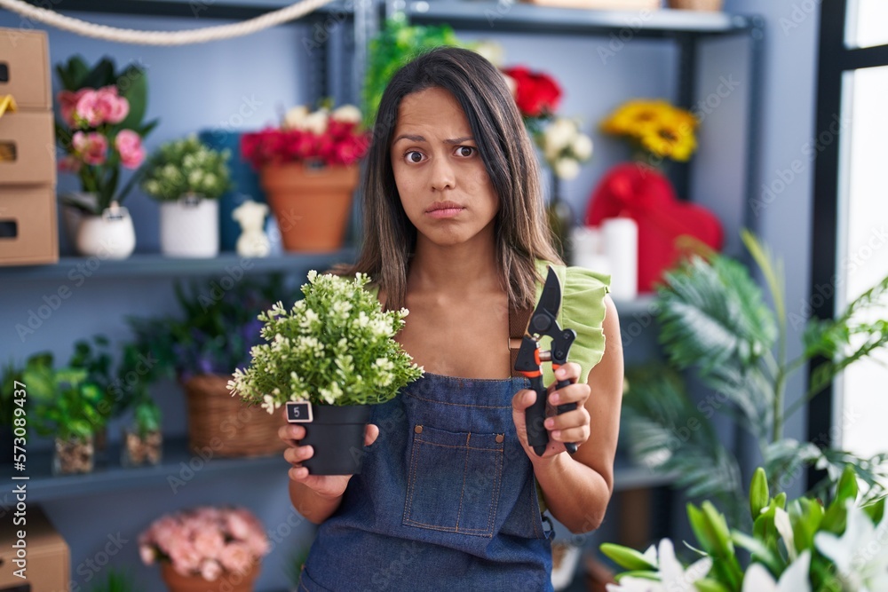 Hispanic young woman working at florist shop skeptic and nervous, frowning upset because of problem. negative person.