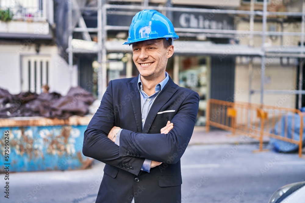 Young man architect smiling confident standing with arms crossed gesture at street