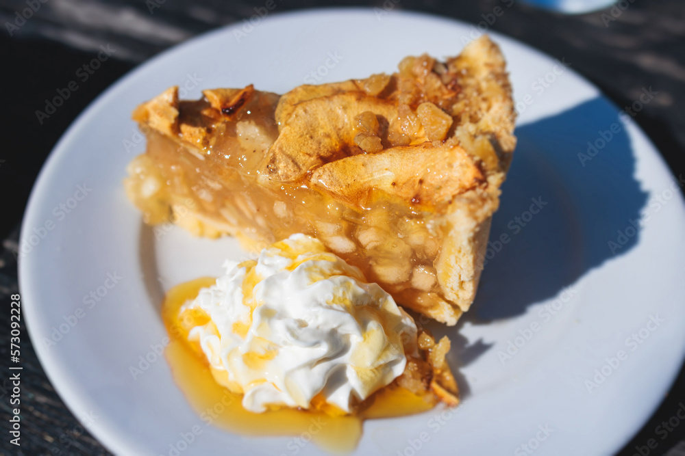 Apple pie slice dessert on a plate, apple slice with ice cream, whipped cream and caramel syrup on a white plate, traditional greek apple sweet pastry served in cafe of Corfu island, Kerkyra, Greece Apple pie slice dessert on a plate, apple slice with ice cream, whipped cream and caramel syrup on a white plate, traditional greek apple sweet pastry served in cafe of Corfu island, Kerkyra, Greece