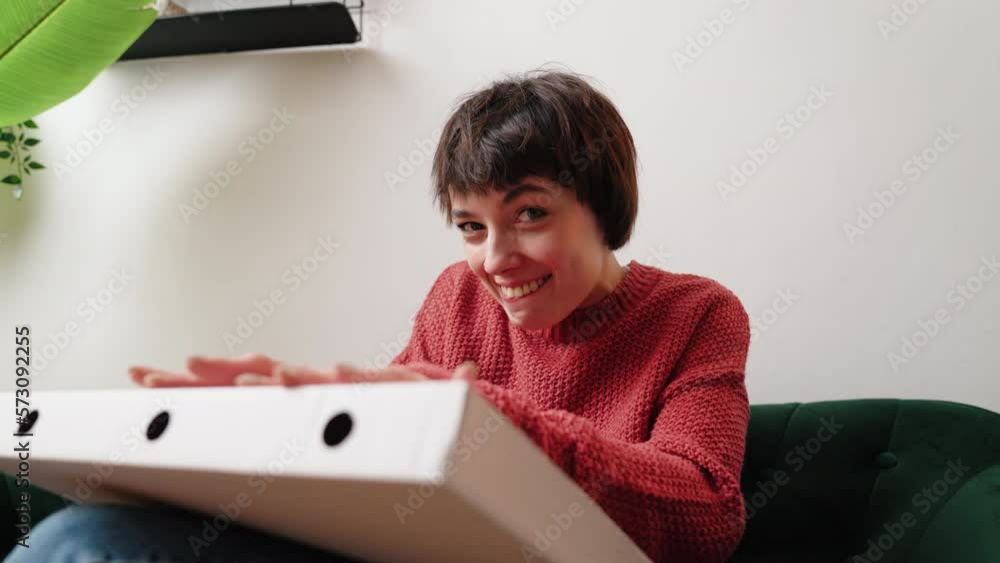 Excited young adult woman in red knitted sweater sitting on green couch with pizza cardboard. Modern interior. High quality 4k footage Excited young adult woman in red knitted sweater sitting on green couch with pizza cardboard. Modern interior. High quality 4k footage