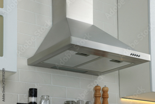 Modern range hood over shelf with spices in kitchen