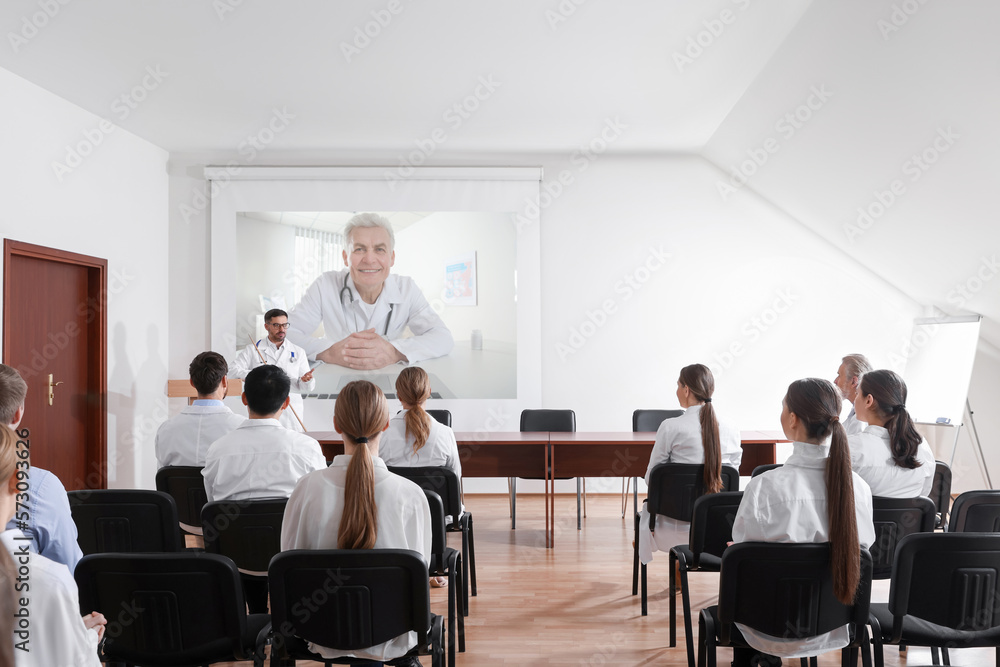 Lecture with online participant. Doctors in meeting room. Using projector for videoconference Lecture with online participant. Doctors in meeting room. Using projector for videoconference