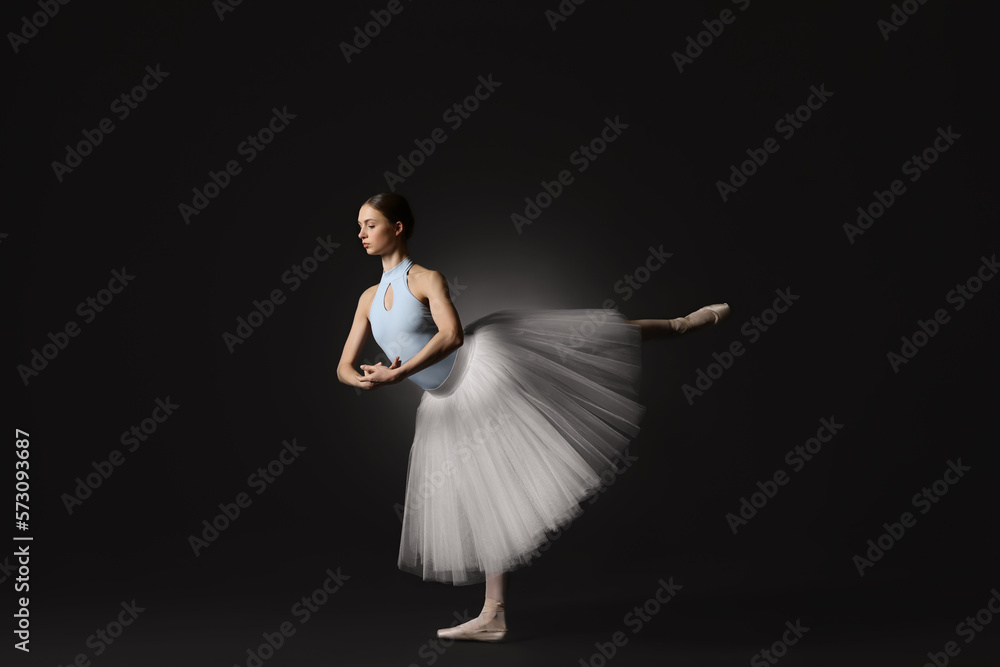 Naklejka premium Young ballerina practicing dance moves on black background