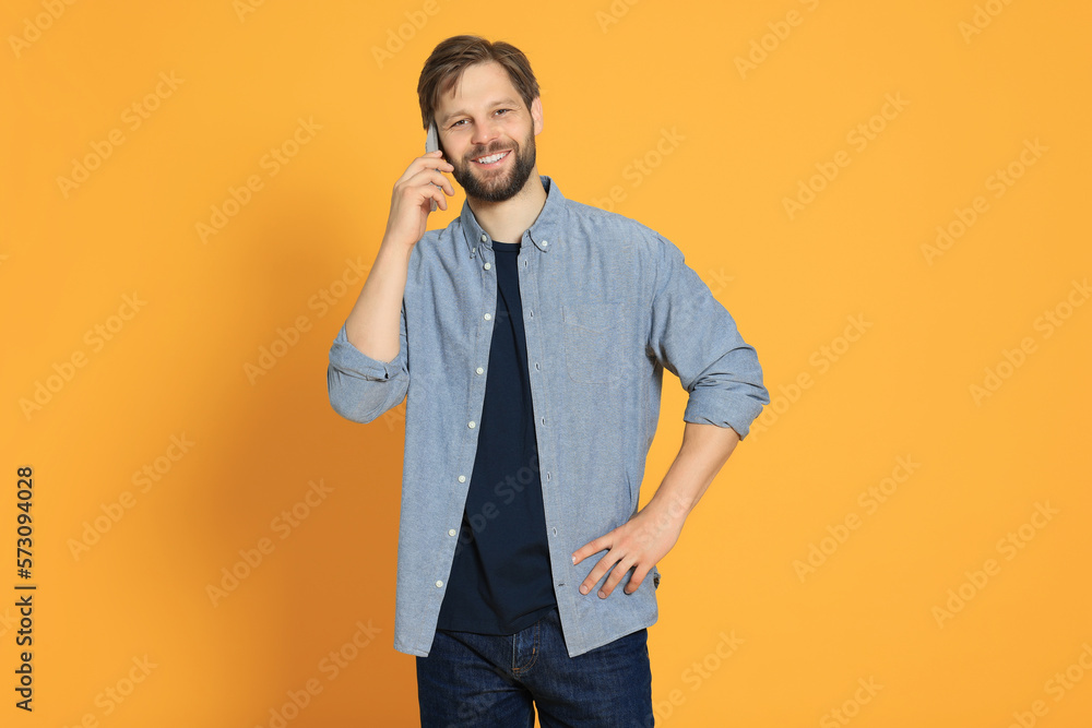 Man talking on smartphone against orange background Man talking on smartphone against orange background